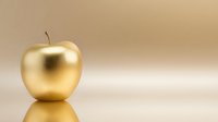Golden apple with metallic finish on reflective surface against warm beige background for luxury branding and premium product concepts.