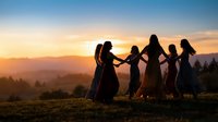Group of diverse women holding hands in circle during golden hour sunset with mountain landscape background for wellness and friendship concepts.