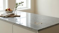 Modern kitchen interior with polished granite countertop surface, white cabinets and natural window light creating elegant cooking space for home design.