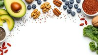 Healthy superfood ingredients frame with avocado, blueberries, nuts, seeds and greens on white background for nutritious meal planning and wellness.