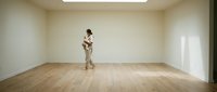Young Asian woman practicing contemporary dance in empty studio room with wooden floor and white walls for creative expression and artistic movement.