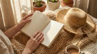 Cozy reading moment with open book, straw hat and coffee cup in sunlit room with plants creating peaceful morning atmosphere for relaxation and leisure.