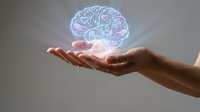 Glowing holographic brain floating above open cupped hands representing artificial intelligence, mental health, neuroscience and cognitive technology concepts.