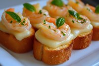 Gourmet shrimp crostini appetizers with creamy sauce and fresh herbs on toasted baguette slices, garnished with basil leaves, served on white plate.