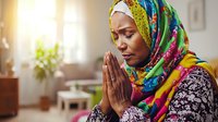Woman wearing colorful headscarf praying with hands together in bright home interior with natural sunlight, spiritual practice and faith concept for wellness and meditation design projects.