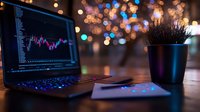 Laptop displaying financial trading chart with bokeh lights background, potted plant and tablet on wooden desk, creating modern workspace atmosphere.