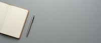 Open notebook with blank pages and silver pen on gray surface, suitable for business planning, education, writing projects, and organizational design layouts.