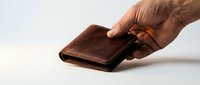 Hand holding a brown leather bifold wallet against a light background, showcasing craftsmanship for finance, shopping, and lifestyle concepts.