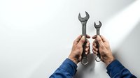 Mechanic hands holding wrenches on white background for repair service maintenance work tools concept isolated ready for design projects.