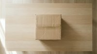 Two kraft cardboard shipping boxes stacked on light wooden surface, overhead view. Suitable for e-commerce, logistics, packaging design, and delivery service marketing materials.