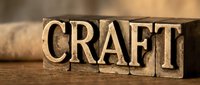 Vintage wooden letterpress blocks spelling CRAFT on rustic wood surface for handmade artisan business branding and creative workshop marketing materials.