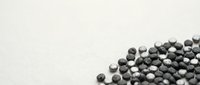 Black lentils scattered on white background creating minimalist food photography composition for healthy cooking and nutrition content.