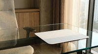 Modern glass dining table with white ceramic plate in contemporary living room interior with beige furniture and natural lighting for home decor.
