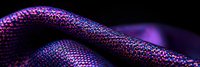 Futuristic metallic fabric with purple and blue iridescent texture on black background creates abstract wave pattern for technology concepts.
