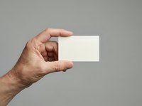 Male hand holding blank white business card against neutral gray background, suitable for branding, corporate identity, and marketing mockup designs.