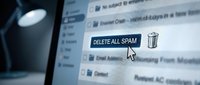 Young professional at desk clicking delete all spam button on computer screen, managing email inbox and removing unwanted messages.