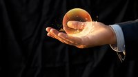 Businessman hand holding glowing golden sphere with digital particles on dark background for technology and innovation concepts.