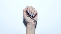 Woman's hand holding makeup brush with dark bristles against white background, ready for cosmetic application or beauty tutorial use.