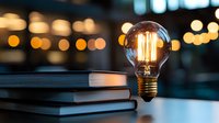 Glowing vintage Edison bulb on stack of books against blurred bokeh lights background, creating atmospheric evening study ambiance. Great for education concepts.