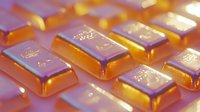 Gold bars arranged in rows with warm lighting and reflective surface creating luxurious metallic shine, suggesting wealth, investment and financial security.