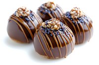 Gourmet chocolate truffles decorated with caramel drizzle, crushed nuts and blue sugar crystals on white background, luxury confectionery close up view.