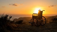 Senior man in wheelchair silhouetted against golden sunset over mountains, symbolizing hope, resilience, and independence during golden hour landscape scene.