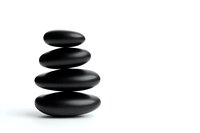 Minimalist black zen stones stacked in balance against white background, creating peaceful spa and wellness composition. Isolated for design use.