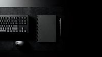 Dark minimalist workspace with black keyboard, notebook, pen and mouse on textured surface for modern office branding and professional design projects.