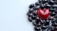 Shiny red heart among black stones on white background, symbolizing uniqueness, love and standing out from crowd. Wellness and spa concept with zen pebbles.