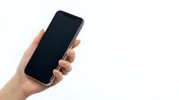 Hand holding modern smartphone with blank black screen isolated on white background for mobile app mockup and digital technology presentations.