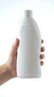 Hand holding white plastic bottle with pump dispenser on isolated background, ready for cleaning product, shampoo, lotion, or detergent branding and packaging design.