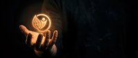 Glowing leaf icon held in open hand against dark background, symbolizing eco-friendly energy, sustainability, and green technology innovation for environmental awareness campaigns.