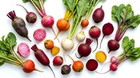 Fresh colorful beets and radishes with green leafy tops arranged on white background. Organic root vegetables for healthy cooking and farm-to-table cuisine.