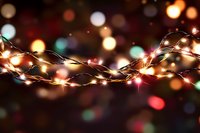 Glowing fairy lights with colorful bokeh background create magical holiday atmosphere. String lights illuminate dark space with warm festive glow.
