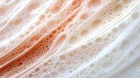 Abstract flowing foam texture with organic bubbles and creamy orange tones creating dynamic movement patterns for modern design backgrounds.