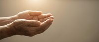 Elderly hands cupped together in prayer or offering gesture against warm golden light background symbolizing hope, faith, spirituality and protection.