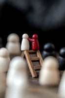 White and red wooden figures on ladder among crowd, symbolizing leadership, mentorship and standing out. Business concept for success and achievement.