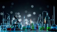 Laboratory glassware with colorful chemical solutions on dark background with bokeh lights for scientific research and education.