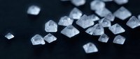 Clear crystal diamonds scattered on dark surface with shallow depth of field creating luxury jewelry and gemstone concept for premium design projects.