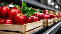 Fresh red apples with green leaves arranged in wooden crates at market display. Bright, glossy fruits showing quality produce and healthy food concept.