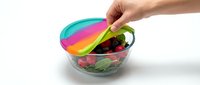Caucasian hand opening colorful rainbow lid on clear bowl filled with fresh salad ingredients, vegetables and greens for healthy eating, meal prep and nutrition concepts.