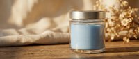 Blue scented candle in glass jar with golden lid on wooden surface with dried flowers and cozy textile background for home decor and relaxation.