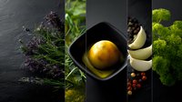 Food collage with fresh herbs, citrus fruit, garlic cloves, peppercorns and parsley in dramatic lighting against dark background, culinary composition.
