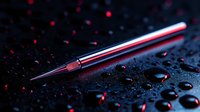 Metallic fountain pen nib with red reflections on dark wet surface with water drops. Dramatic lighting and bokeh effects create moody artistic composition.