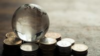 Crystal globe surrounded by stacked coins representing global finance, international investment, world economy and financial growth opportunities.