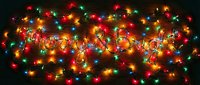 Merry and Bright text formed with colorful glowing Christmas lights on dark wooden background, festive holiday decoration concept.