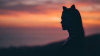 Young woman silhouette with cat ears against vibrant sunset sky. Anime cosplay character profile at golden hour for creative projects and fantasy themes.