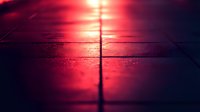 Dramatic red sunset reflection on wet surface creates abstract minimalist composition with strong leading line dividing symmetrical scene in moody atmosphere.