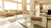 Bright modern living room with welcome sign and keys on glass table, sunlit interior with neutral tones for real estate and hospitality concepts.
