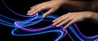 Female hands reaching toward glowing blue and purple light streams on dark background for technology and digital innovation concepts.